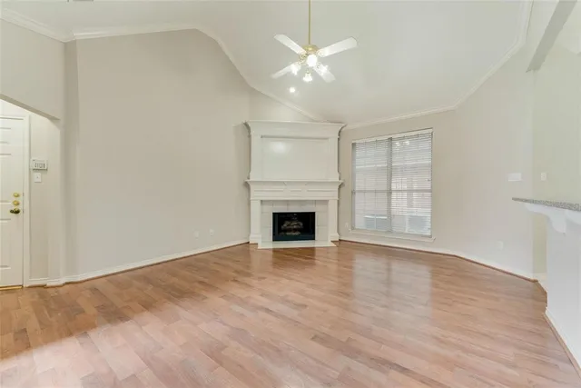 a view of an empty room with wooden floor fireplace and a window