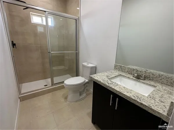 a bathroom with a granite countertop sink a toilet and shower