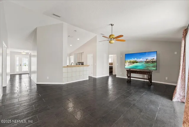 a view of an empty room with a window and wooden floor