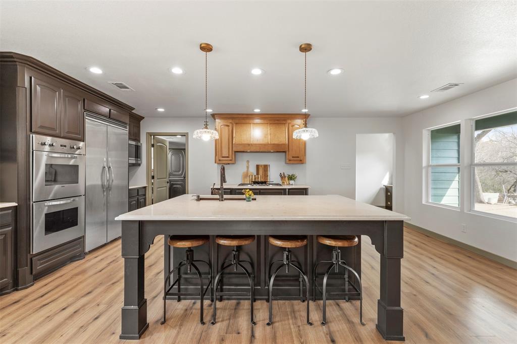 a kitchen with stainless steel appliances kitchen island a wooden floor and white cabinets