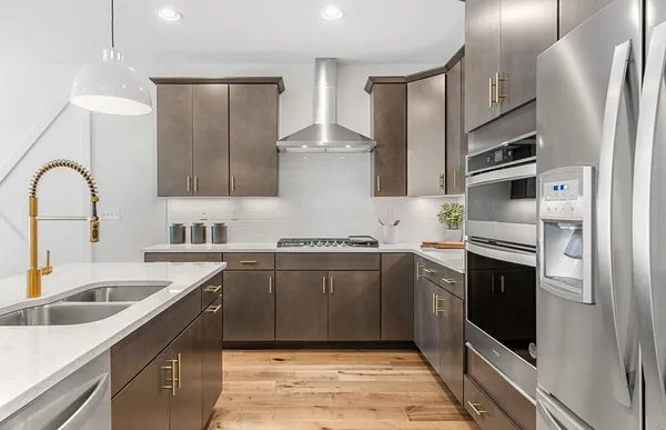 a kitchen with stainless steel appliances granite countertop a sink a stove a refrigerator and cabinets