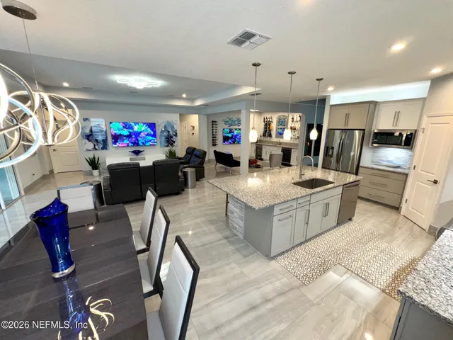 a kitchen with stainless steel appliances granite countertop a stove a sink a refrigerator and chairs