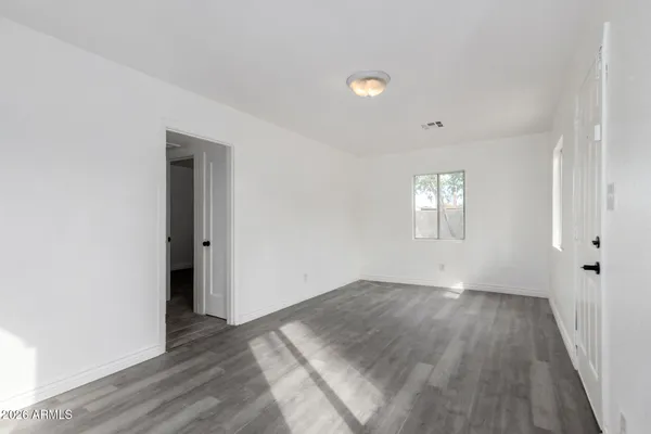 an empty room with wooden floor and windows