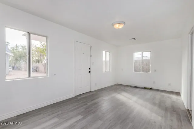 a view of an empty room with wooden floor and windows