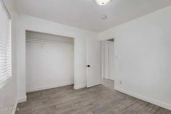 a view of an empty room with wooden floor and closet