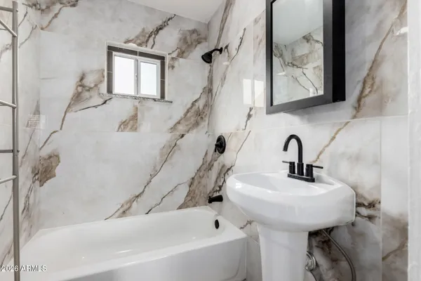 a bathroom with a sink and mirror with bathtub