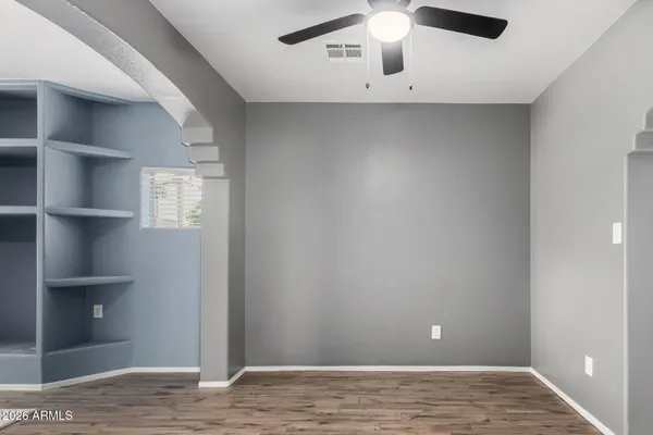 a view of an empty room with window and wooden floor