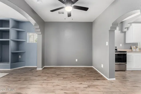 a view of an empty room and kitchen space with wooden floor