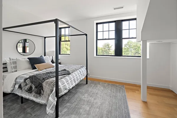 a bedroom with a bed two windows and wooden floor