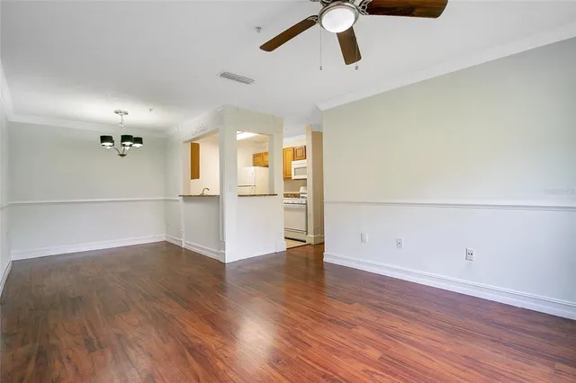 an empty room with wooden floor cabinet and windows