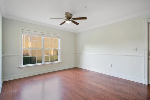 an empty room with wooden floor fan and windows