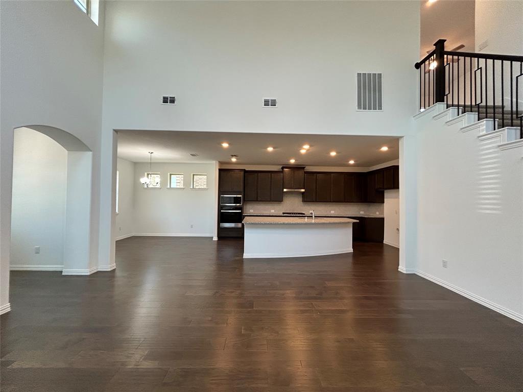 1448 Sun Gdn Way Justin, TX 76247 - Photo 3 of 28 Unfurnished living room featuring dark wood-type flooring and arched walkways