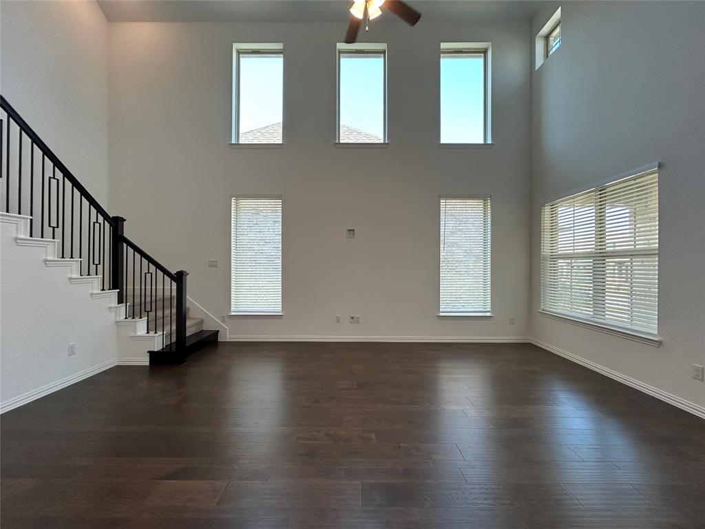 1448 Sun Gdn Way Justin, TX 76247 - Photo 5 of 28 Unfurnished living room with dark wood-type flooring, ceiling fan, plenty of natural light, and a high ceiling