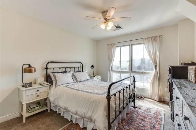 a bedroom with a bed a chandelier and a flat tv screen on dresser