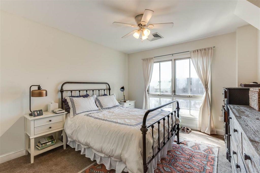 711 Clinton Street, Unit 6A Hoboken, NJ 07030 - Photo 9 of 15 a bedroom with a bed a chandelier and a flat tv screen on dresser