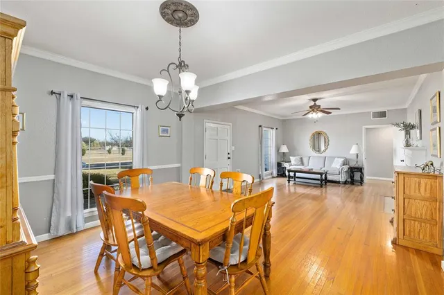 a dining room with furniture a chandelier and wooden floor