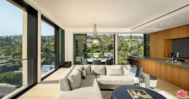 a living room with couches large flat screen tv and a floor to ceiling window