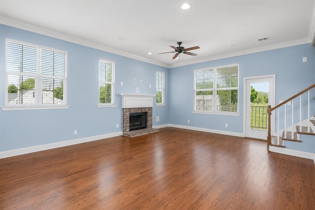 179 Ranchtown Road Elm Grove, LA 71051 - Photo 9 of 26 Spacious living area featuring wood-finish flooring, a brick fireplace with a white mantel, multiple windows with blinds, a ceiling fan, and access to an outdoor area