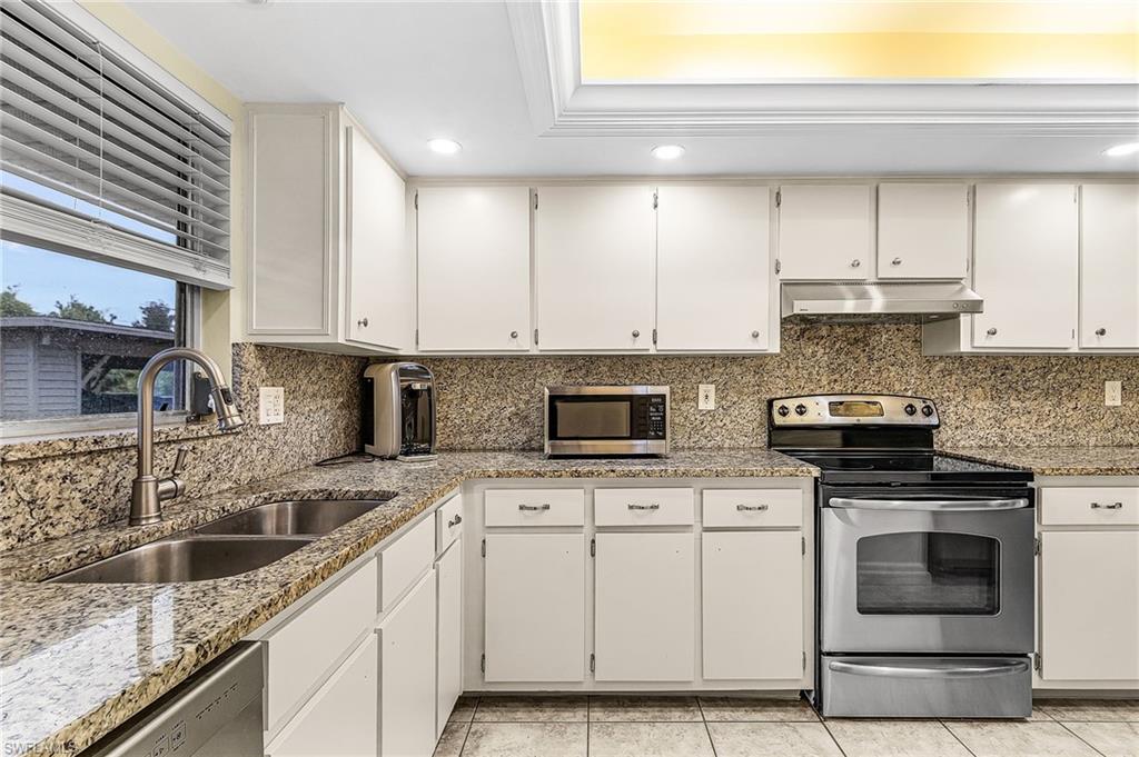 5917 Littlestone Court, Unit 115 North Fort Myers, FL 33903 - Photo 9 of 24 a kitchen with granite countertop a stove sink and cabinets