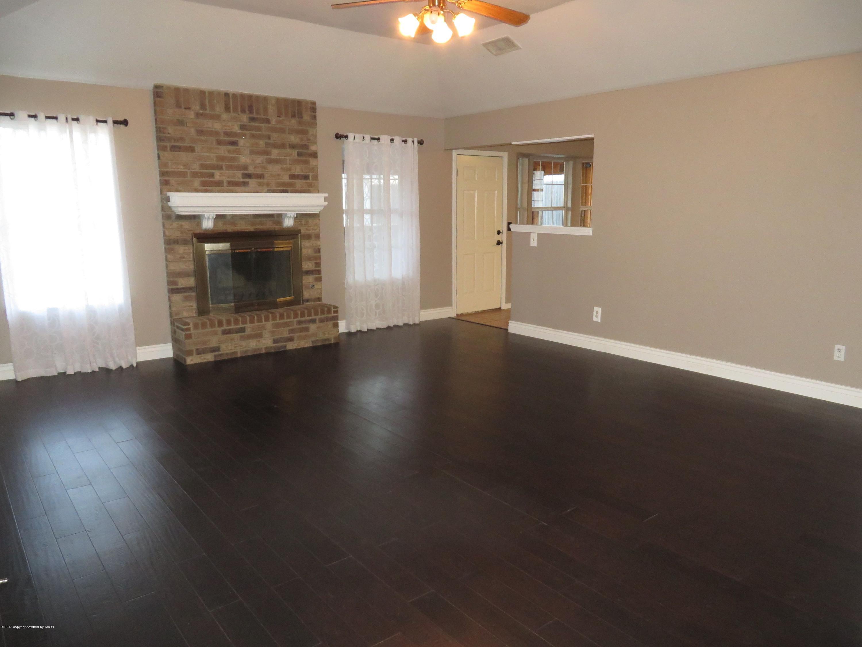 4213 Rincon Avenue Amarillo, TX 79110 - Photo 4 of 9 an empty room with wooden floor fireplace and windows