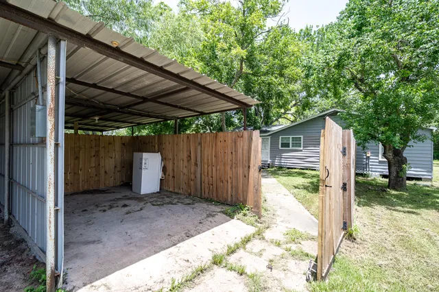 a view of a backyard with wooden fence and a large tree