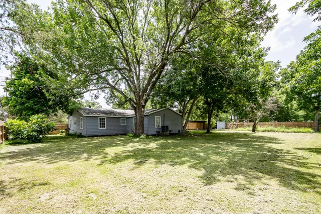a view of a house with a big yard and large trees