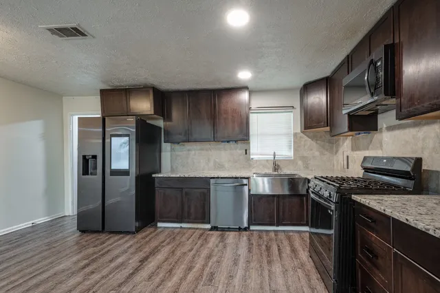 a kitchen with stainless steel appliances granite countertop wooden cabinets a refrigerator and a stove