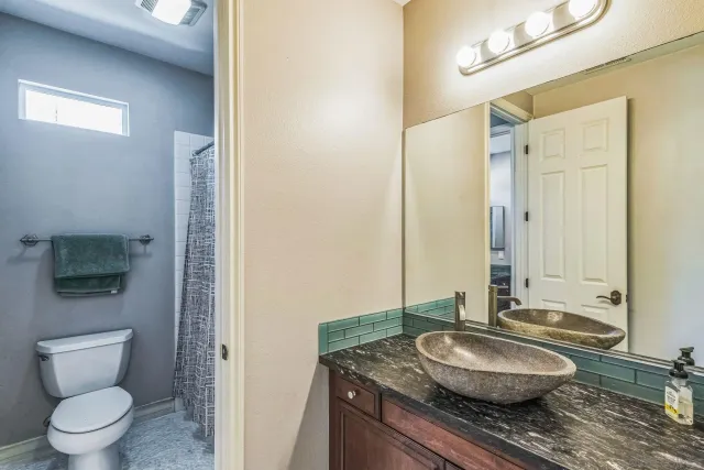 a bathroom with a granite countertop sink a toilet and a mirror