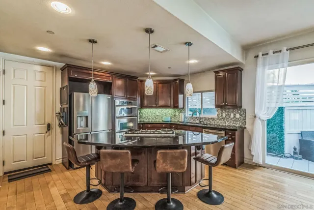 a kitchen with stainless steel appliances kitchen island granite countertop a table chairs sink and cabinets