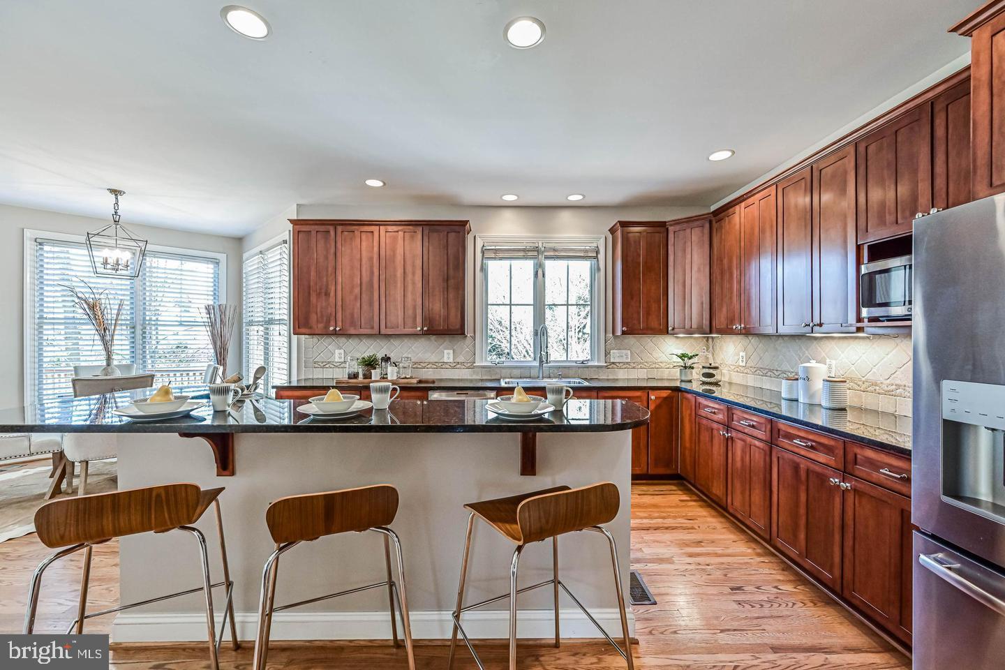 6516 76th Place Cabin John, MD 20818 - Photo 13 of 46 a kitchen with stainless steel appliances granite countertop wooden cabinets a stove a sink a window and dining table