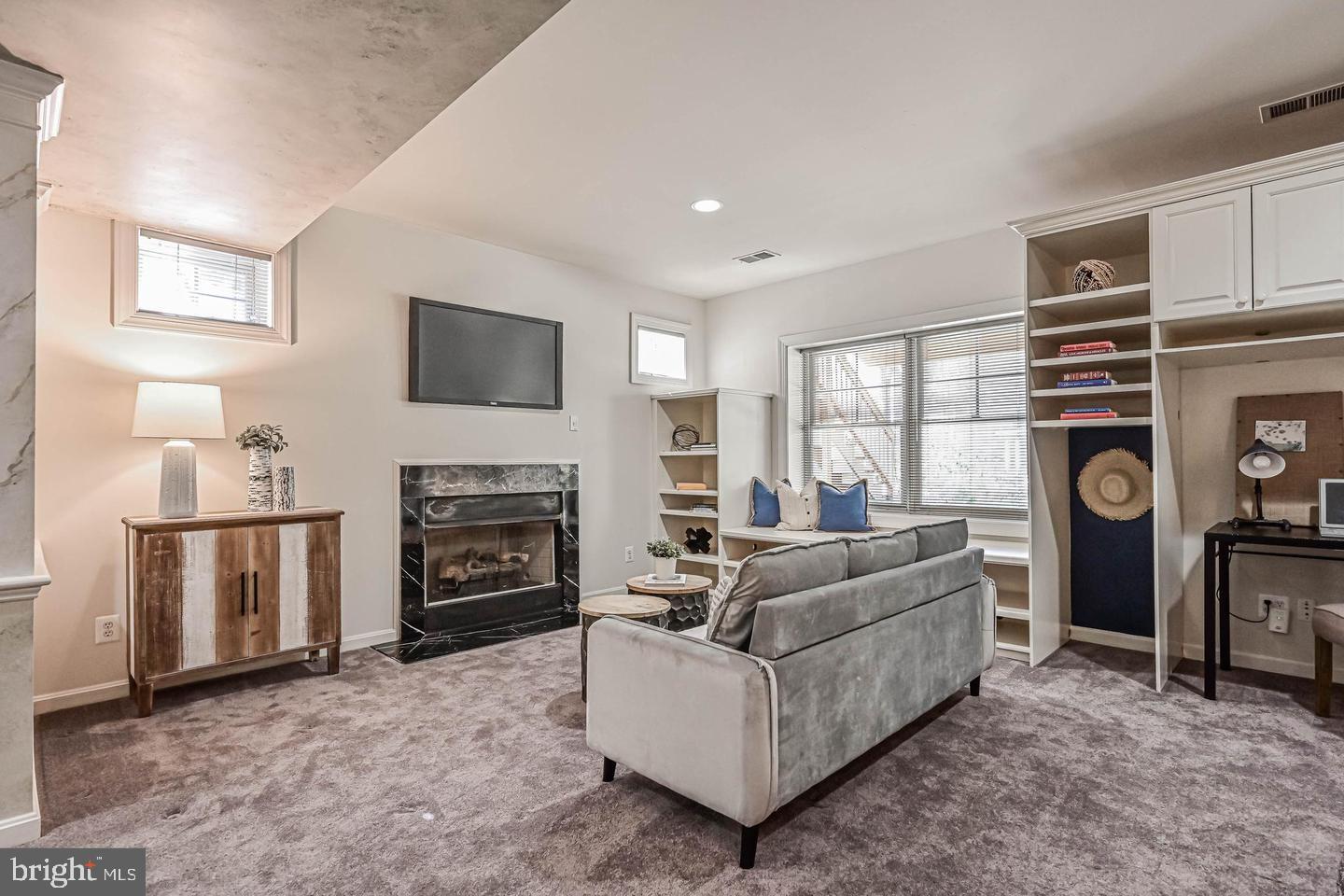 6516 76th Place Cabin John, MD 20818 - Photo 33 of 46 a living room with furniture a fireplace and a flat screen tv