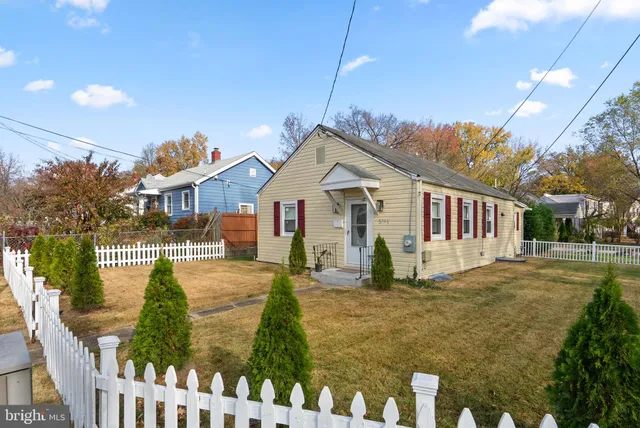 a view of a white house next to a yard with wooden fence