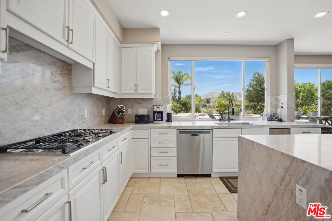 4040 Leighton Point Road Calabasas, CA 91301 - Photo 4 of 47 a kitchen with white cabinets a stove a sink and a window