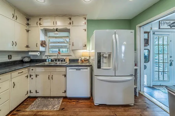 a kitchen with stainless steel appliances a refrigerator a sink dishwasher and wooden cabinets with wooden floor