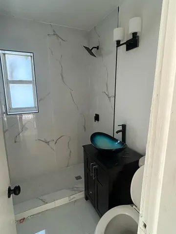 a bathroom with a granite countertop sink a toilet and shower