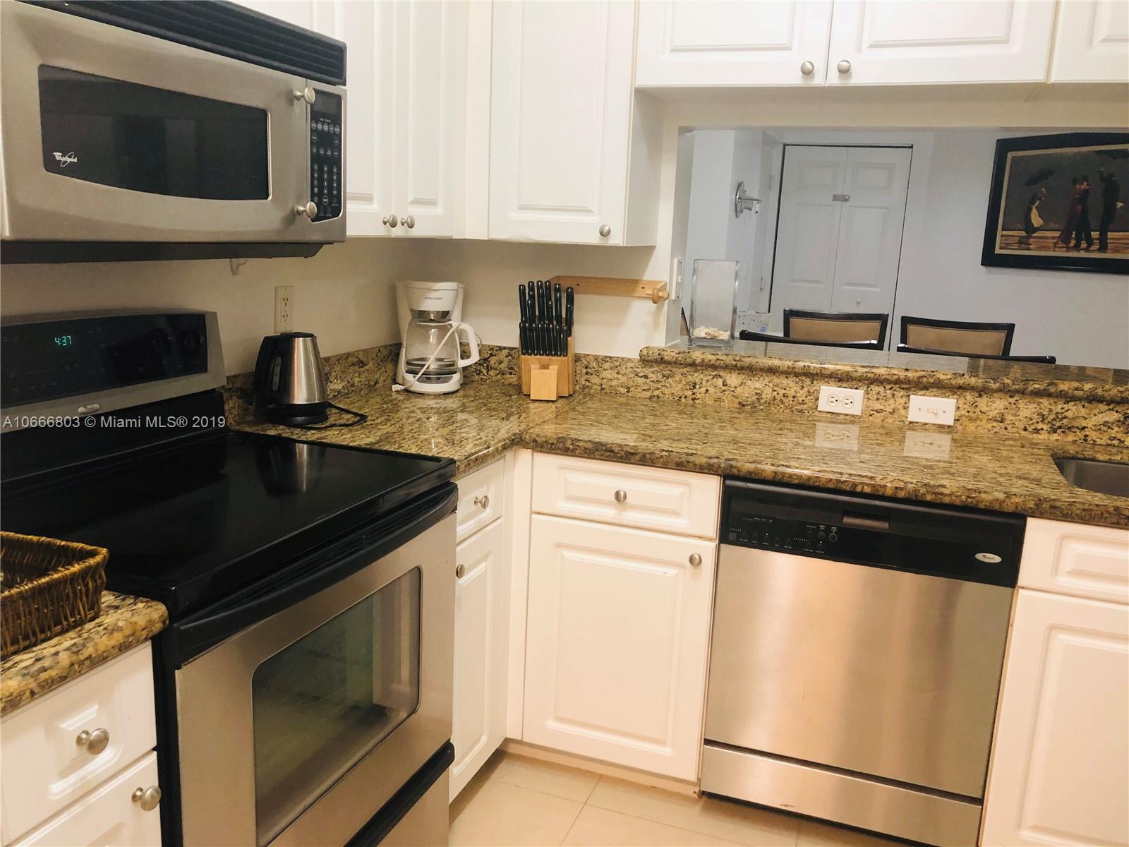 17100 North Bay Road, Unit 1212 Sunny Isles Beach, FL 33160 - Photo 11 of 24 a kitchen with granite countertop a sink dishwasher stove and microwave with wooden floor