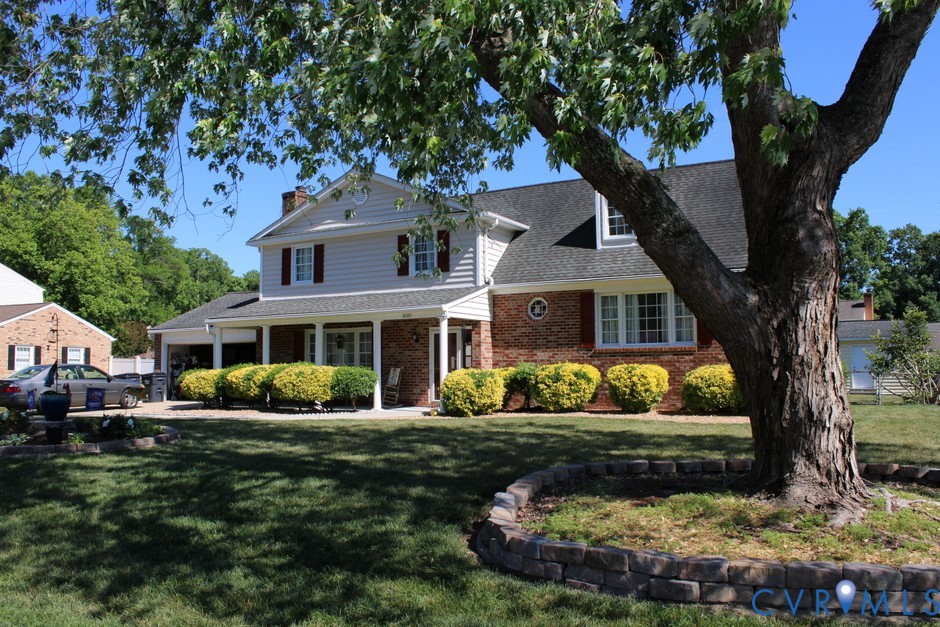 a front view of a house with a garden and trees