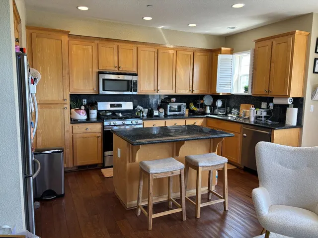 a kitchen with granite countertop a table chairs microwave and cabinets