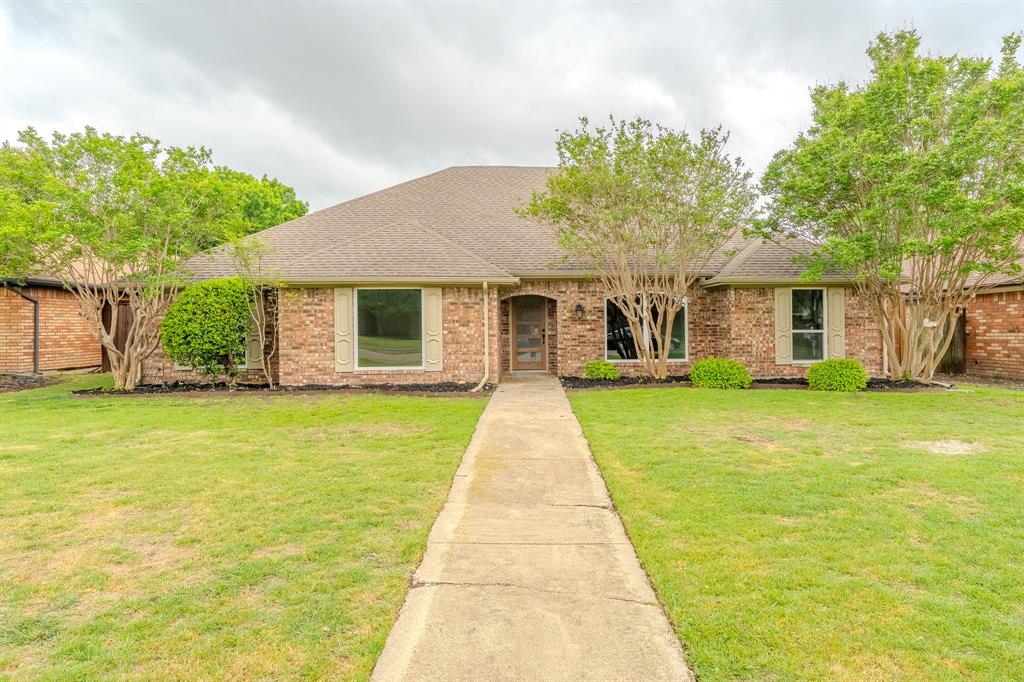 Single story home with brick siding, a shingled roof, and a front yard