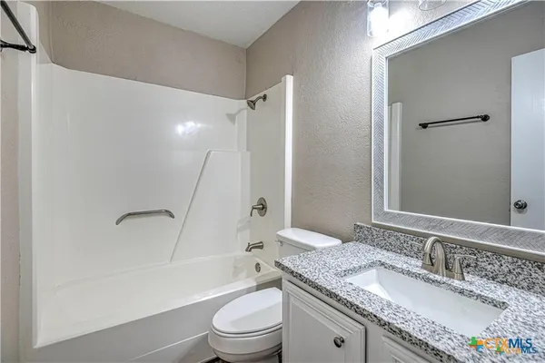 a bathroom with a granite countertop sink a mirror toilet and bathtub