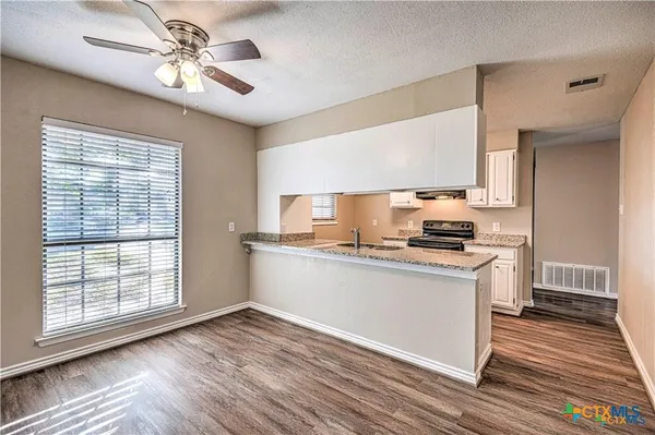 a kitchen with stainless steel appliances granite countertop a sink a stove a refrigerator cabinets and wooden floor