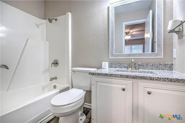 a bathroom with a granite countertop toilet sink and mirror
