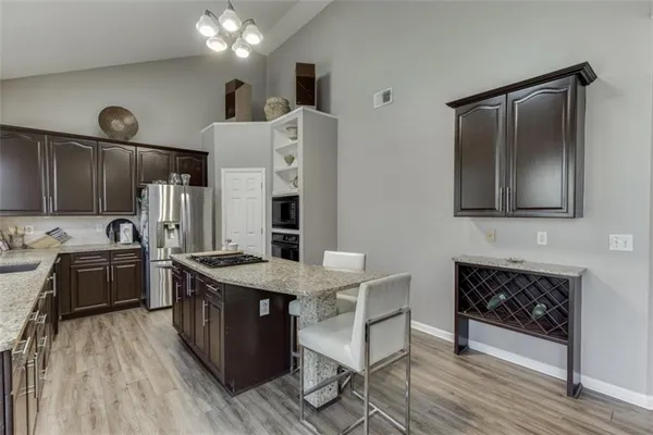 a kitchen with stainless steel appliances granite countertop a refrigerator a stove a sink dishwasher a dining table and chairs with wooden floor