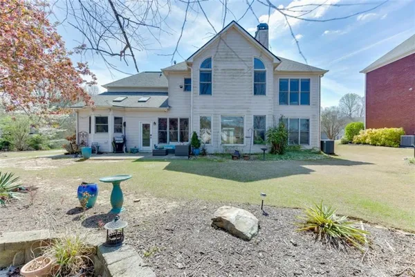 a front view of a house with a yard outdoor seating and covered with trees