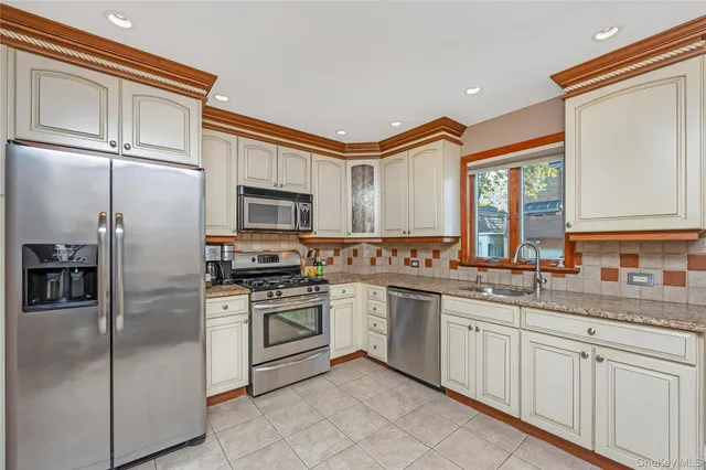 a kitchen with stainless steel appliances granite countertop a refrigerator a stove a sink and a microwave