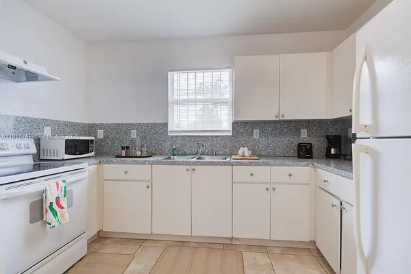 a kitchen with granite countertop white cabinets and refrigerator