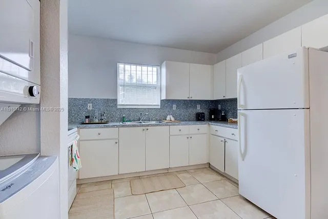 a kitchen with granite countertop white cabinets and refrigerator