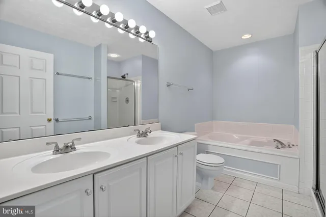 a bathroom with a toilet a sink a mirror a bathtub and vanity