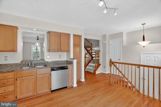 a kitchen with granite countertop a refrigerator a sink and white cabinets