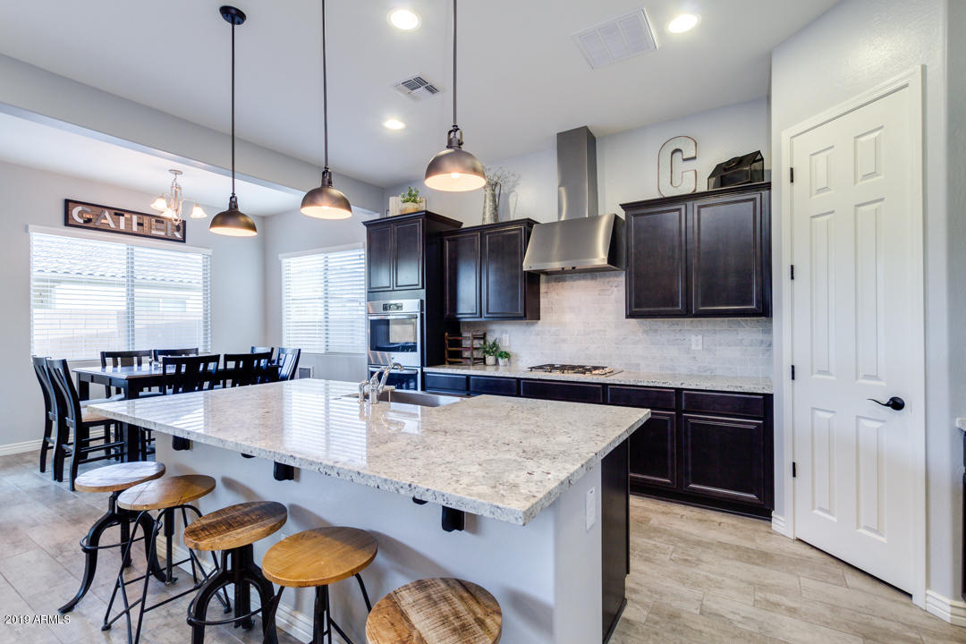 2665 East Stacey Road Gilbert, AZ 85298 - Photo 18 of 56 a kitchen with stainless steel appliances granite countertop a stove a refrigerator a sink a dining table and chairs with wooden floor